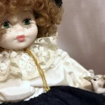 vecchia bambola di porcellana con capelli ricci e merletti